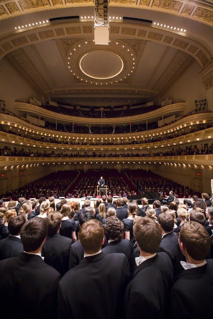 A conductor’s view from inside the choir toward a full house at Carnegie Hall.